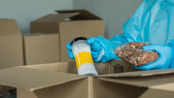 Volunteer prepares food kits from long-storage products - Фото, изображение