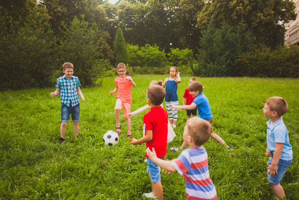 Boys and girls are playing soccer in the summer park - Foto, Imagen