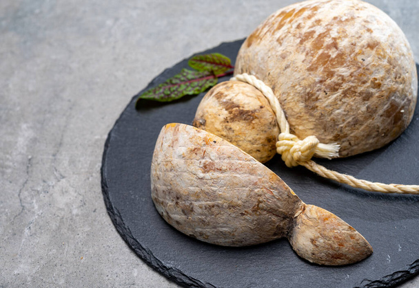 Italiaanse halfharde gerijpte caciocavallo kaas, handgemaakt en gerijpt in natuurlijke ondergrondse grotten in Apulië van dichtbij - Foto, afbeelding