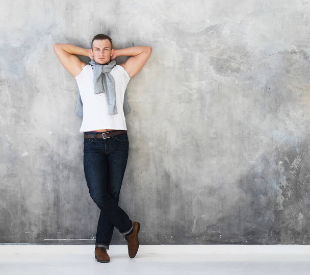 man, fashion model posing in white t-shirt in jeans in full length - Photo, image