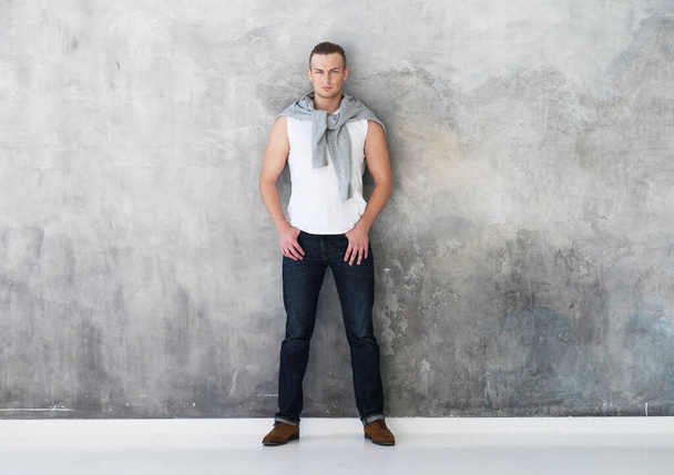 man, fashion model posing in white t-shirt in jeans in full length - Photo, image