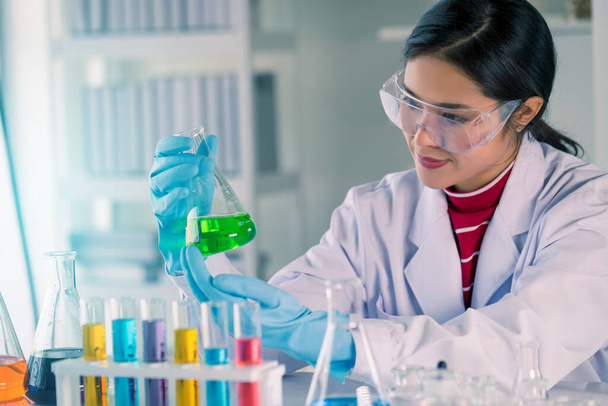 Jovem tecnólogo médico asiático fêmea fazendo testes com tubo de teste enquanto faz pesquisa em laboratório de ciências
 - Foto, Imagem