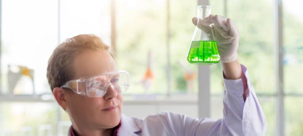 Junge kaukasische Wissenschaftler testen im Reagenzglas, während sie im Wissenschaftslabor forschen.  - Foto, Bild