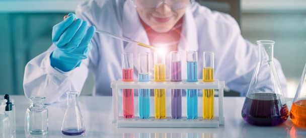 Junge asiatische Medizintechnologin testet im Reagenzglas, während sie im Wissenschaftslabor forscht - Foto, Bild