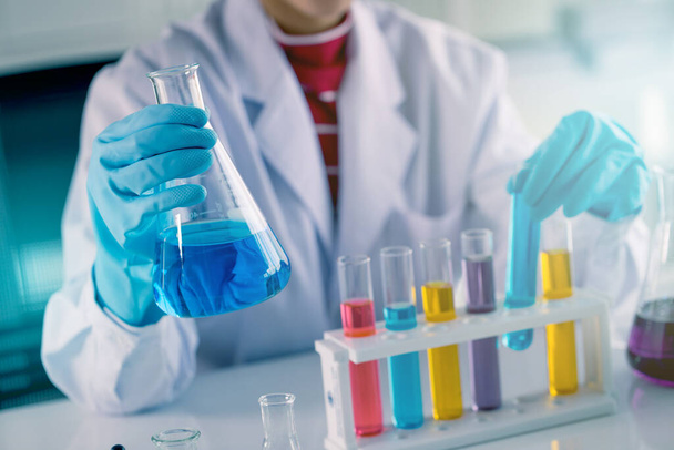 Junge asiatische Medizintechnologin testet im Reagenzglas, während sie im Wissenschaftslabor forscht - Foto, Bild