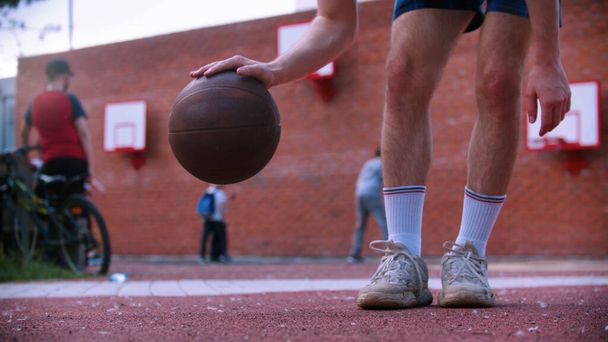 Młody człowiek na boisku do koszykówki uderza piłkę - Zdjęcie, obraz