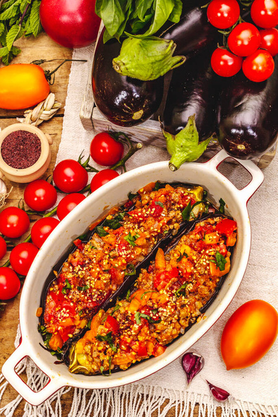 Karniyarik traditionele Turkse gerechten. Gevulde aubergines met gehakt, tomaat, groente en sesamzaad. Oude houten tafel, bovenaanzicht - Foto, afbeelding