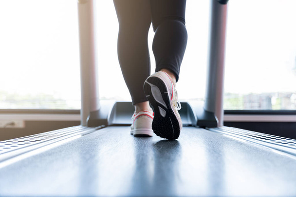 Acercamiento pies femeninos con zapatillas de deporte corriendo en la cinta de correr en el gimnasio de fitness. Estilo de vida de la dieta, pérdida de peso, músculo del estómago, concepto saludable
. - Foto, imagen