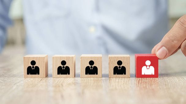 Close up hand choosing people icons on cube wooden toy blocks concepts human resources for business organizations and leadership. - Photo, Image
