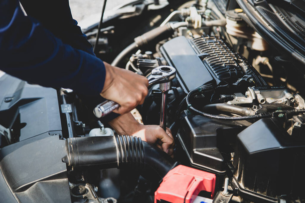 Automekaanikko käyttää jakoavainta auton moottorin korjaamiseen. käsitteet auton hoito korjata korjaus palvelu ja vakuutus. - Valokuva, kuva