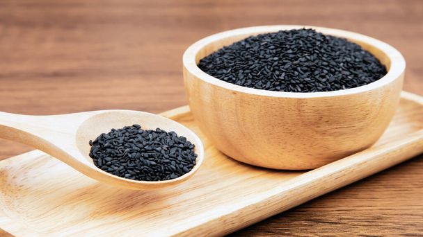 Черные семена кунжута в деревянной ложке для здорового питания и диеты. - Фото, изображение