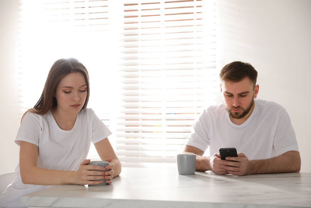 Young man preferring smartphone over his girlfriend at home. Relationship problems - Fotoğraf, Görsel