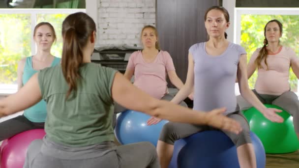 安定したボールの上に座っている若い妊婦のグループの中ショットとリラクゼーションのための呼吸法を練習 - 映像、動画