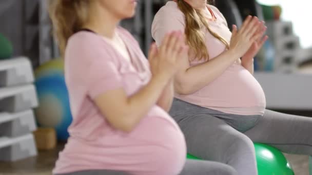 Dengeli topların üzerinde otururken iki sağlıklı hamile kadının yoga pozisyonlarını denerken orta derece çekimini yap. - Video, Çekim
