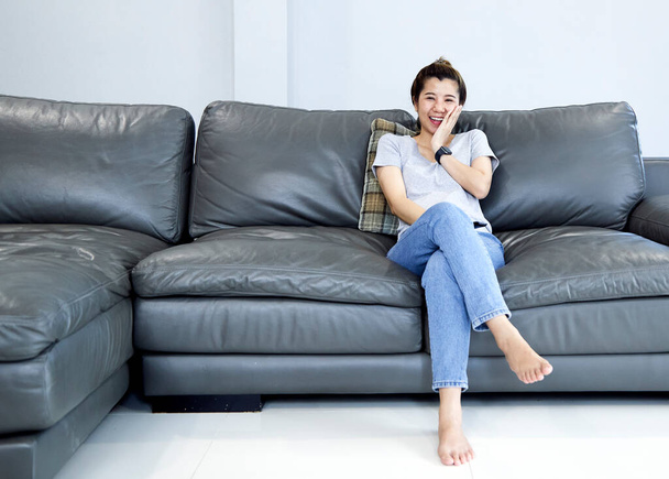 Молодая женщина отдыхает дома, смотрит телевизор и меняет канал с помощью пульта дистанционного управления
 - Фото, изображение