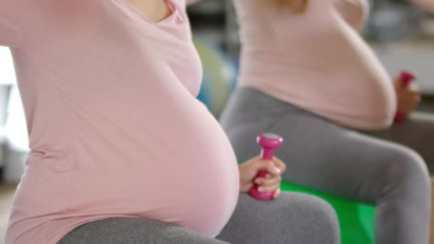 Dengeli topların üzerinde oturan ve fitness sınıfında yan esneme egzersizleri yapan hamile kadınları yukarı kaldır. - Video, Çekim