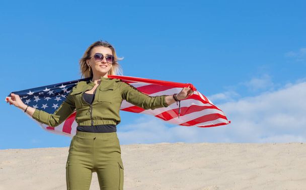 Woman with USA flag against blue sky and sandy. America Independence Day. - Foto, Imagen