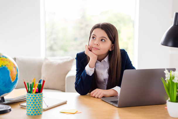 Photo of little pretty student school girl distracted look up notebook online lesson not listen teacher flying far away distance quarantine study stay home living room classroom indoors - Foto, Bild