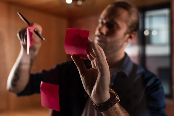 επιλεκτική εστίαση ροζ αυτοκόλλητες σημειώσεις κοντά επιχειρηματίας με στυλό  - Φωτογραφία, εικόνα