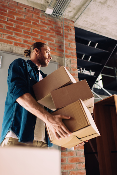 низкий угол обзора бизнесмена, держащего коробки во время переезда в новый офис
  - Фото, изображение