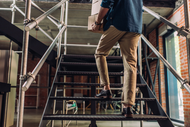 περικοπή άποψη του επιχειρηματία κρατώντας κουτιά χαρτοκιβωτίων, ενώ το περπάτημα στις σκάλες στο γραφείο - Φωτογραφία, εικόνα