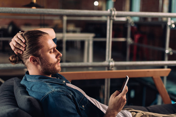 profile of businessman chilling on sofa and using smartphone in office  - Valokuva, kuva