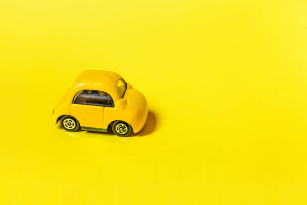 Eenvoudig ontwerp gele vintage retro speelgoedauto geïsoleerd op gele kleurrijke achtergrond. Automobiel en vervoer symbool. Stadsverkeer levering concept. Kopieerruimte - Foto, afbeelding