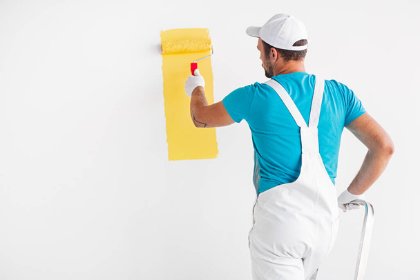 Painter painting wall in yellow color - Foto, Bild