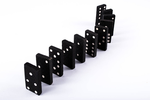 Zwarte domino tegels in een rij geïsoleerd op witte achtergrond - Foto, afbeelding