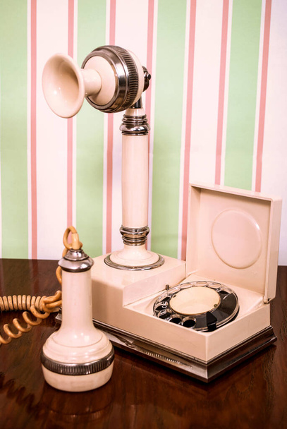Vintage witte telefoon op houten bureau en retro achtergrond - Foto, afbeelding