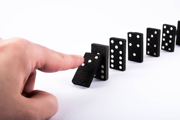 Los dedos empujan fichas de dominó y caen aislados sobre un fondo blanco. Concepto de efecto dominó
 - Foto, imagen