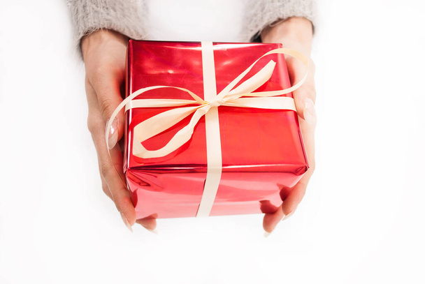 Female hand holding red box present with white bow - 写真・画像