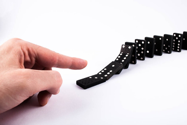 Vinger push dominostenen tegels en ze vallen geïsoleerd op een witte achtergrond. Domino-effect - Foto, afbeelding