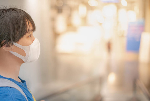 Az ázsiai nő sebészeti maszkot visel, lemegy a pláza lépcsőjén, mozgólépcsőt használva a nyilvános területen. Biztonsági tudatosság a mindennapi élet koncepciójában. - Fotó, kép