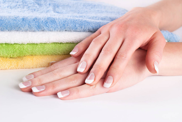 Woman hands with french manicure next to colorful towels - Photo, Image