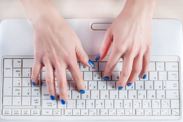 Female hands typing on white laptop keyboard. Top view, close up - Photo, image