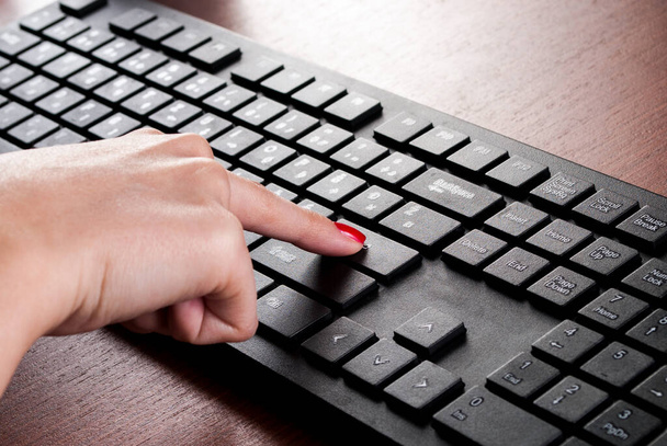 Girl vinger druk op Enter knop op computer toetsenbord op houten bureau. Sluiten. - Foto, afbeelding