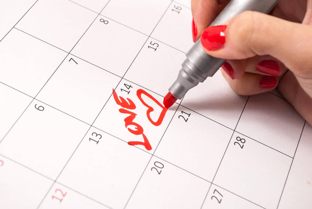 Filles main avec crayon dessin coeur et mot amour dans le calendrier pour la Saint-Valentin - Photo, image
