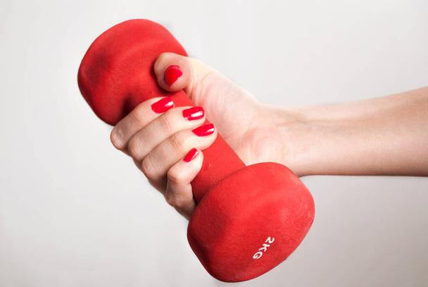 Female holding red dumbbell in hand isolated on white background. Close up - Photo, Image