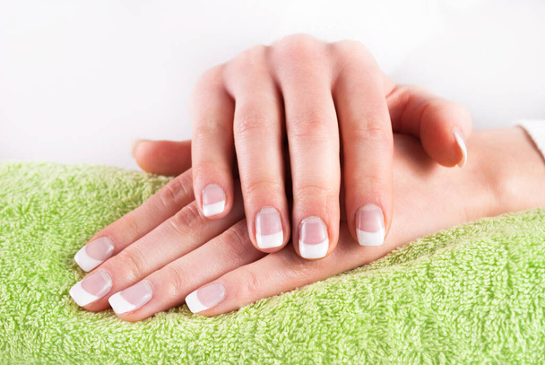 Franse manicure nagels handen op groene handdoek - Foto, afbeelding