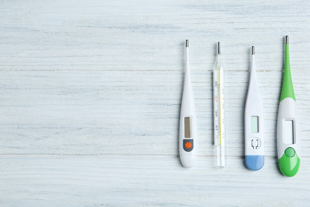 Different thermometers on white wooden background, flat lay. Space for text - Foto, Imagen