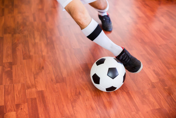 Szelektív összpontosítani labdát futsal játékos fut lőni labdát a cél a fa padlón a sportcsarnokban. Beltéri foci sportcsarnok.  - Fotó, kép