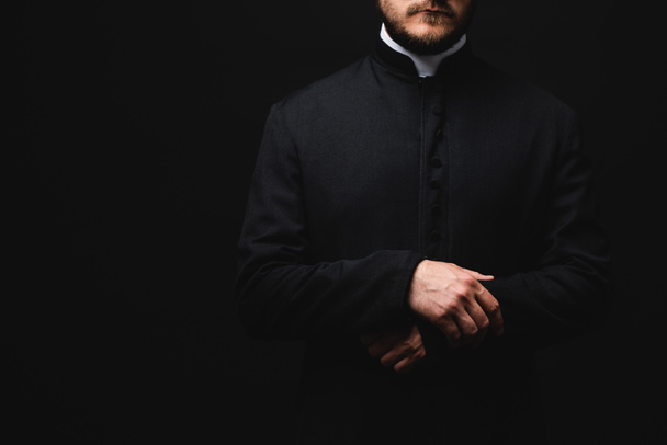 oříznutý pohled na kněze stojícího izolovaně na černém  - Fotografie, Obrázek