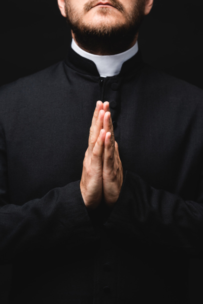 cropped view of priest with praying hands isolated on black  - Fotoğraf, Görsel