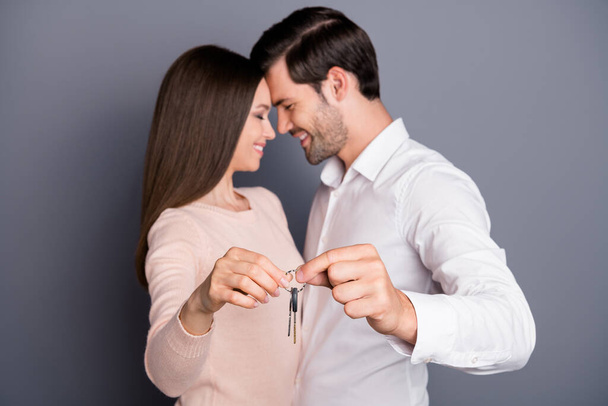 Photo beautiful lady handsome guy in love hold keys chain relocation concept buy flat house just married couple owners happy together wear shirt pullover pants isolated grey color background - Foto, Bild