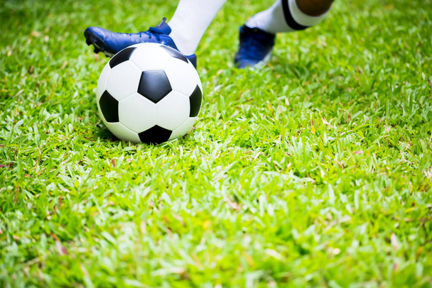 Focista ellenőrzés lőni labdát a zöld fű a cél. Focista edzés a meccsre. Focista a fociakadémián. - Fotó, kép