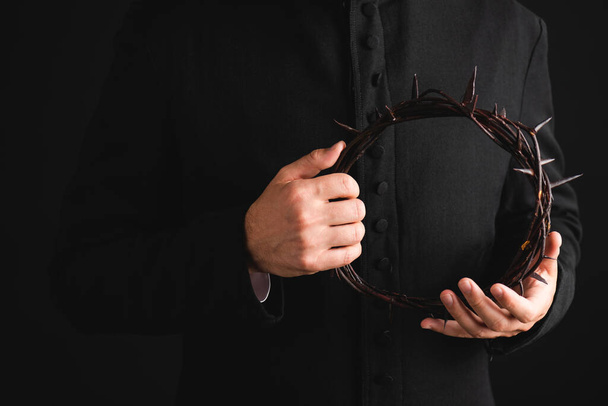 cropped view of priest holding sharp wreath with spikes isolated on black  - Fotoğraf, Görsel