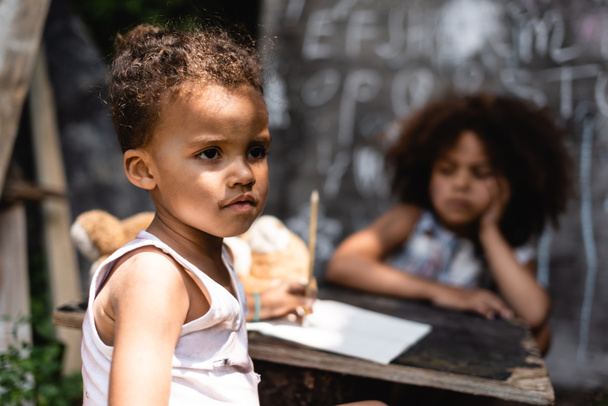 selective focus of poor african american child near curly sister - Foto, imagen