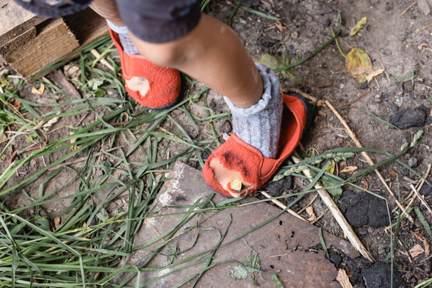 cropped view of poor kid standing in ripped shoes  - Photo, Image