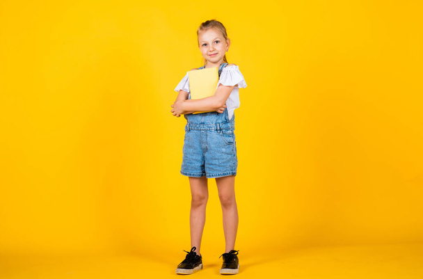 favorite subject. Kid with smart look and casual outfit. modern education concept. inspired with idea. Girl read the book. Back to school and childhood concept. Pupil on yellow background - Fotó, kép